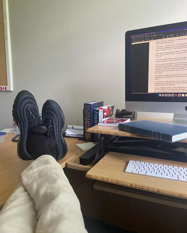 Feet up at a desk while a D-Day story is open on the monitor