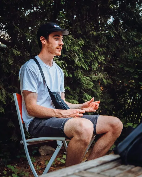 Michael seated outdoors in a white T-shirt, talking during an interview